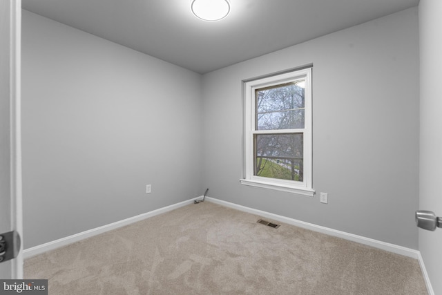 empty room featuring carpet, visible vents, and baseboards