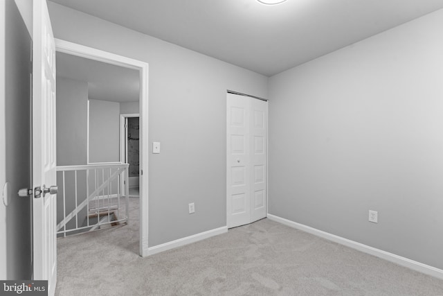 unfurnished bedroom with carpet, a closet, and baseboards