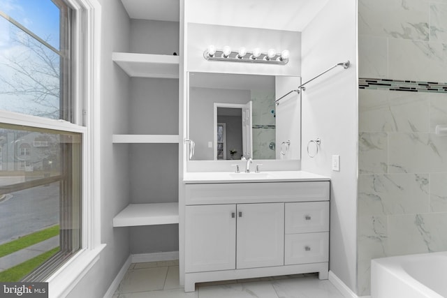 full bath featuring marble finish floor, baseboards, a tub, and vanity