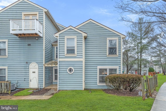 view of front of home with a balcony, a front lawn, and central AC unit