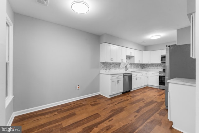 kitchen featuring tasteful backsplash, white cabinetry, stainless steel appliances, and a sink