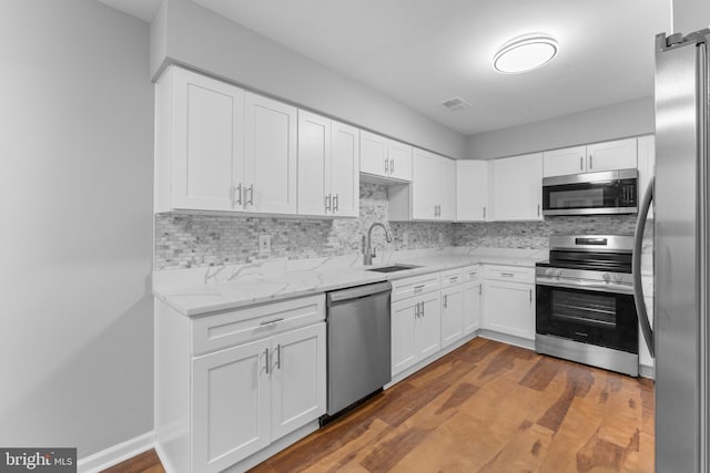 kitchen featuring visible vents, dark wood-style floors, stainless steel appliances, white cabinetry, and a sink