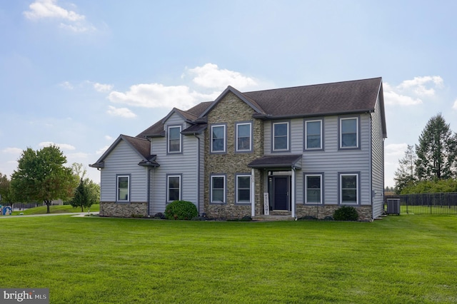 view of front facade featuring stone siding, central AC unit, a front yard, and fence