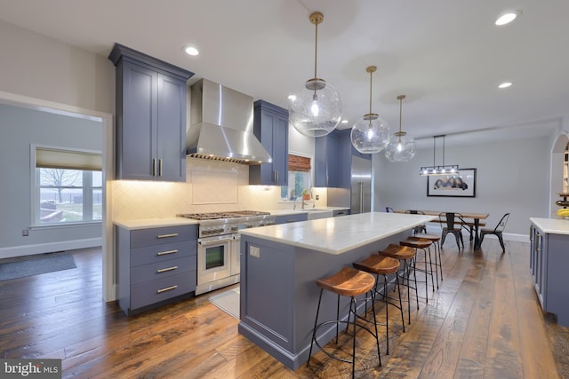 kitchen with dark wood-style floors, a kitchen island, range with two ovens, wall chimney range hood, and tasteful backsplash