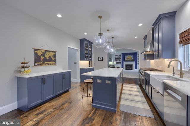 kitchen featuring blue cabinetry, a fireplace, a sink, dishwasher, and a center island