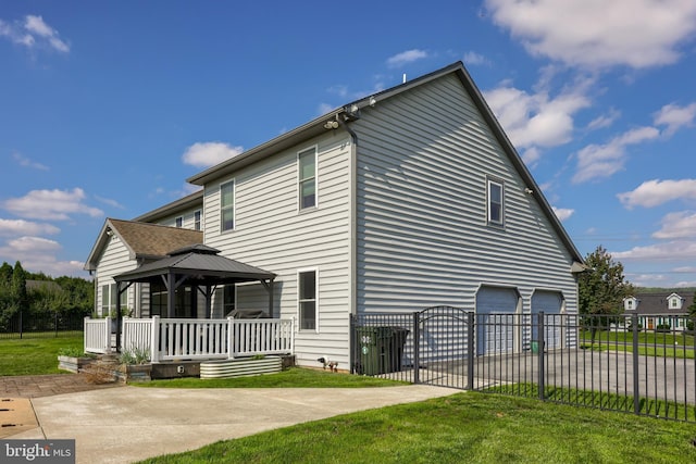 view of property exterior featuring a gazebo, a yard, an attached garage, and fence