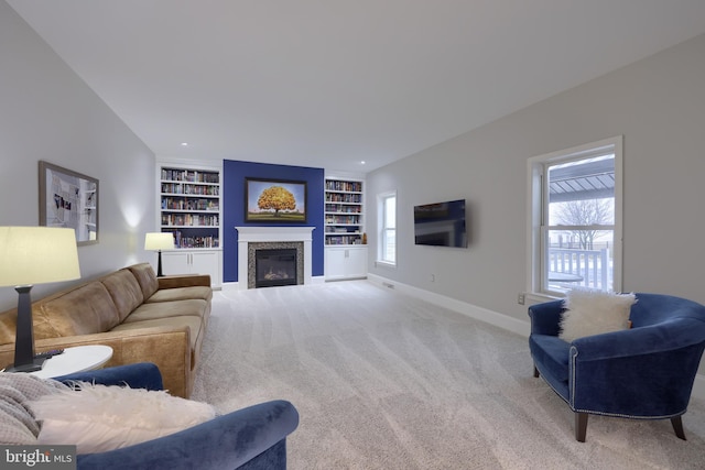 living room featuring built in shelves, baseboards, carpet floors, recessed lighting, and a glass covered fireplace