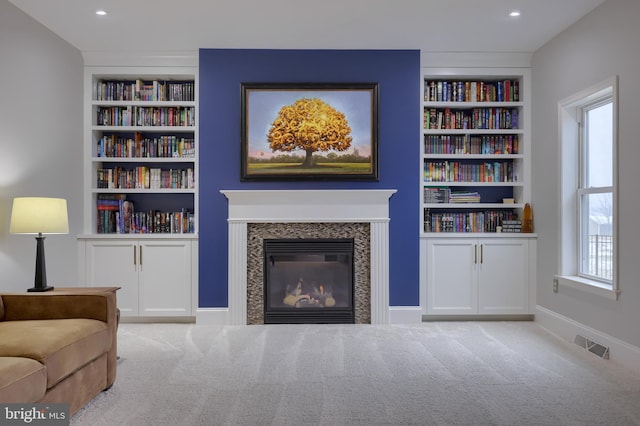 living room featuring built in features, a premium fireplace, carpet, and visible vents