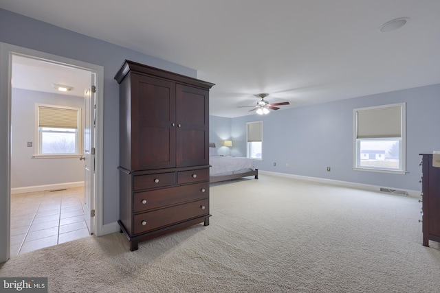 bedroom featuring light tile patterned floors, baseboards, light colored carpet, and a ceiling fan