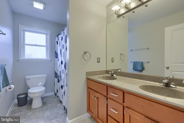 full bathroom with double vanity, toilet, baseboards, and a sink