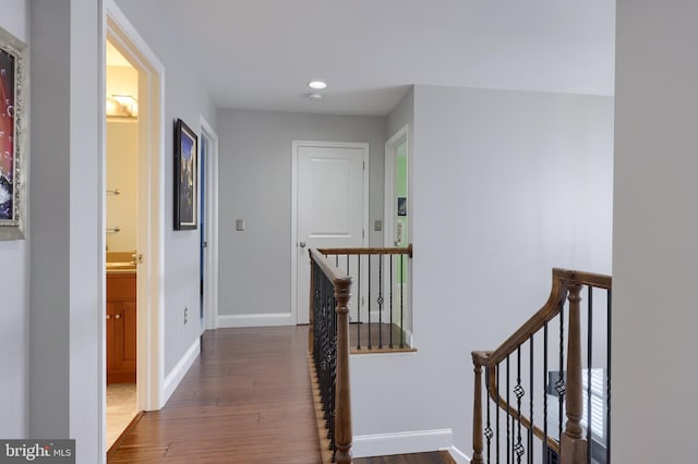 corridor with recessed lighting, baseboards, an upstairs landing, and wood finished floors