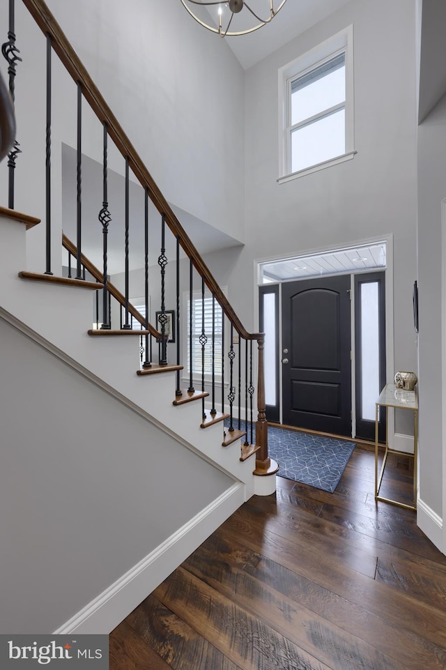 entryway featuring stairway, wood finished floors, baseboards, and a towering ceiling