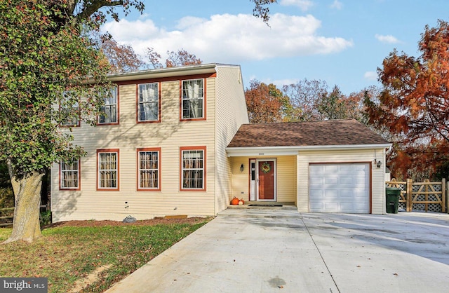 view of front facade featuring a garage, concrete driveway, and fence