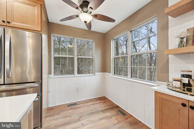 kitchen featuring light wood-style flooring, freestanding refrigerator, a wainscoted wall, and visible vents