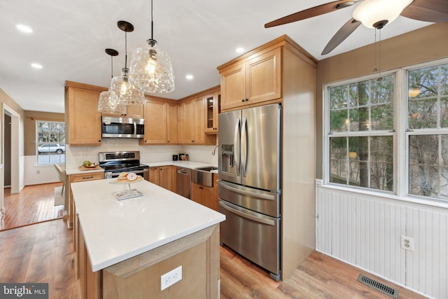 kitchen featuring appliances with stainless steel finishes, a center island, light countertops, and light wood-style flooring