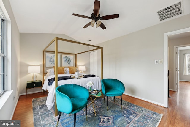 bedroom featuring baseboards, visible vents, vaulted ceiling, and wood finished floors