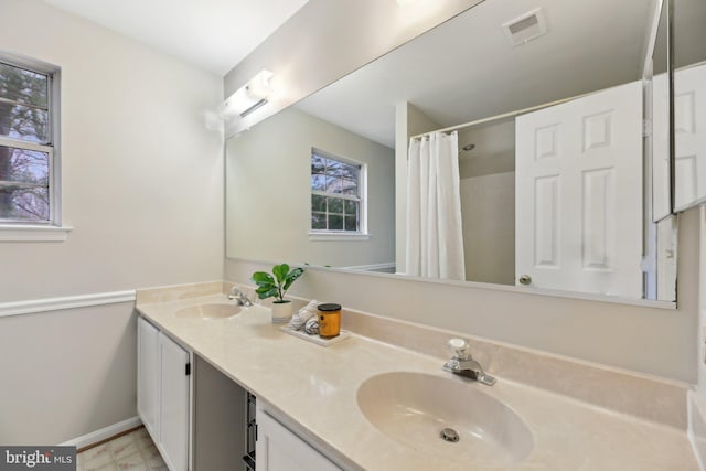 bathroom with double vanity, a sink, visible vents, and baseboards