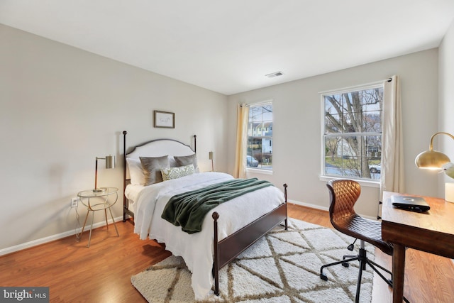 bedroom featuring visible vents, baseboards, and wood finished floors