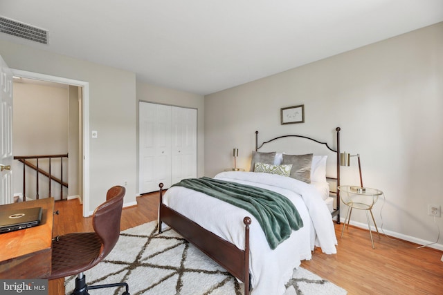 bedroom with baseboards, a closet, visible vents, and wood finished floors