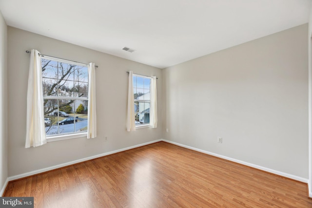 unfurnished room with visible vents, baseboards, and wood finished floors