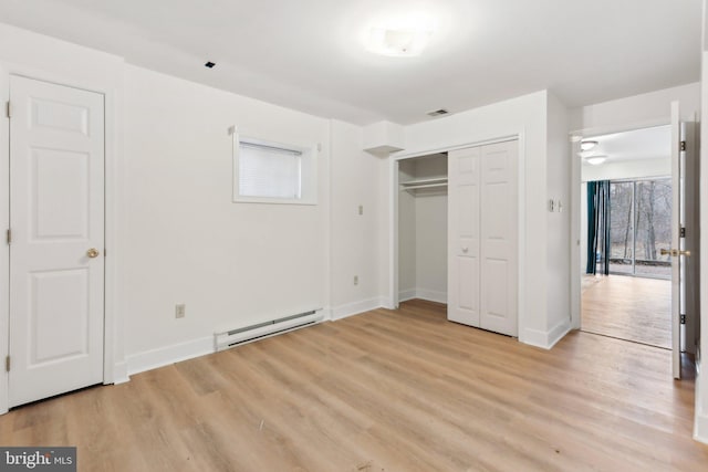 unfurnished bedroom featuring light wood-style floors, a closet, baseboards, and baseboard heating