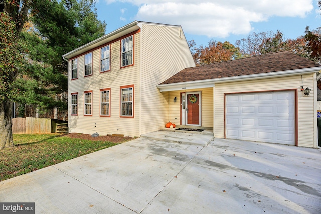 view of front of home with concrete driveway, an attached garage, and fence