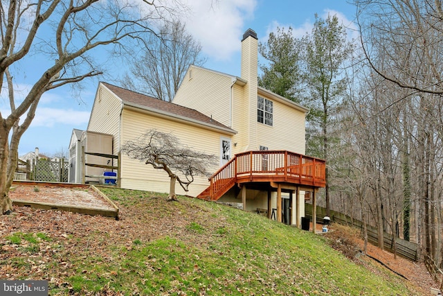 back of property featuring a deck, a chimney, and stairs