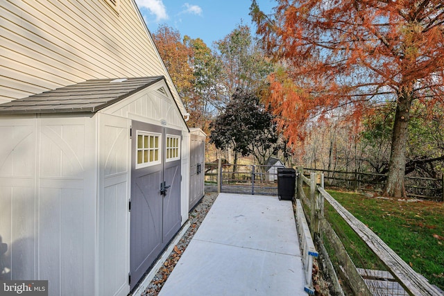 view of side of home featuring a gate, fence, and an outdoor structure