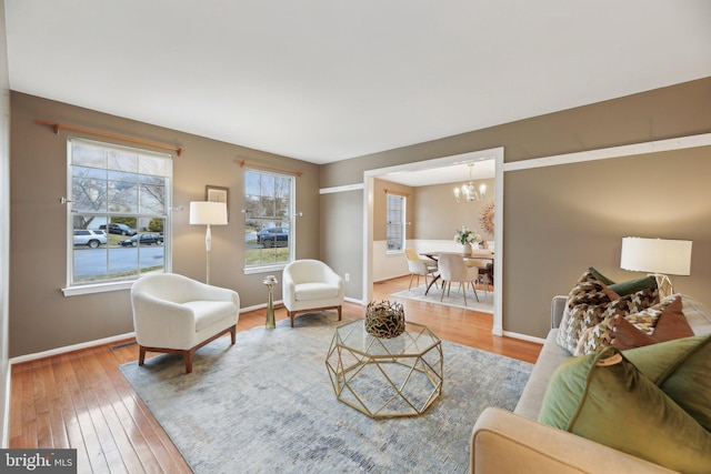 living room featuring wood-type flooring, baseboards, and a chandelier