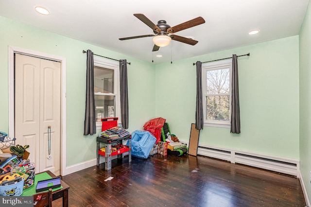 recreation room featuring baseboard heating, recessed lighting, baseboards, and wood finished floors