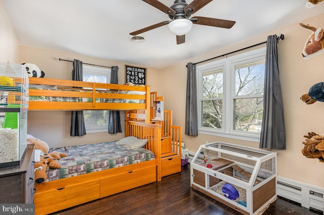 bedroom featuring visible vents, baseboard heating, and hardwood / wood-style floors