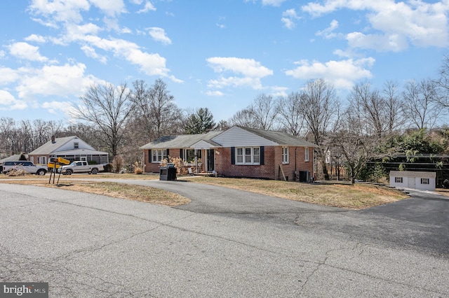 view of front of house with brick siding, central air condition unit, driveway, and a front yard