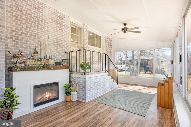 exterior space with ceiling fan and a glass covered fireplace