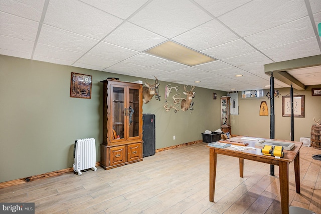 rec room with a drop ceiling, baseboards, and light wood finished floors