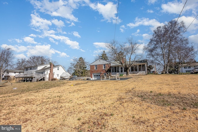 view of yard with a garage, a deck, and a sunroom