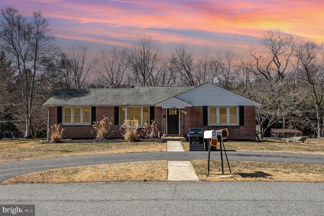 view of front of house with brick siding, driveway, a shingled roof, and a front yard