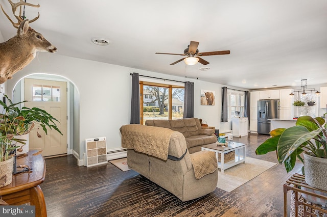 living area with dark wood-style floors, baseboards, visible vents, arched walkways, and ceiling fan