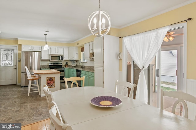 dining room with wainscoting, crown molding, and an inviting chandelier