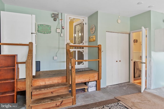 bedroom featuring a closet, concrete floors, and freestanding refrigerator
