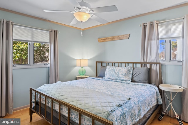 bedroom featuring ceiling fan, wood finished floors, baseboards, and ornamental molding