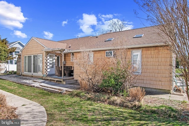 back of property featuring a lawn, a shingled roof, and a pergola