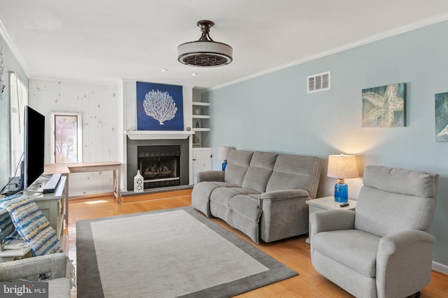 living room with a fireplace, wood finished floors, and ornamental molding