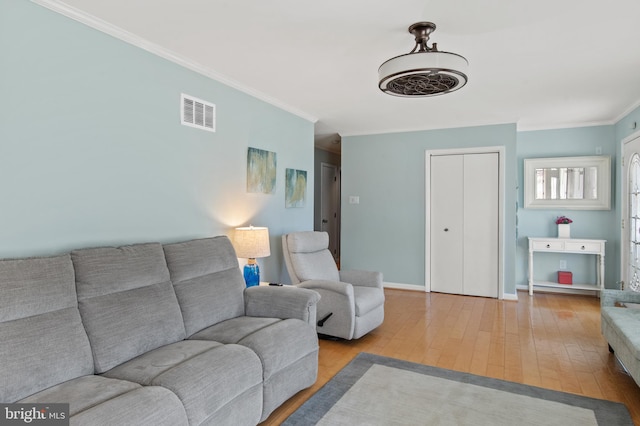 living area with crown molding, wood finished floors, visible vents, and baseboards