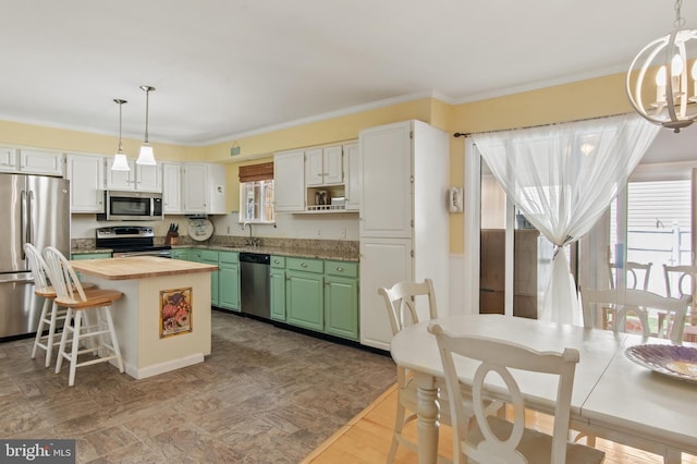 kitchen with a sink, a kitchen island, stainless steel appliances, an inviting chandelier, and wooden counters