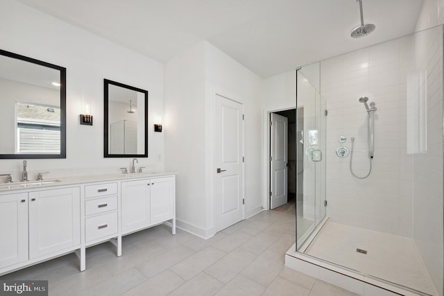 full bath with a stall shower, a sink, baseboards, and double vanity