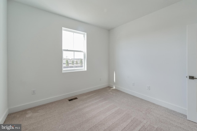 carpeted empty room featuring baseboards and visible vents