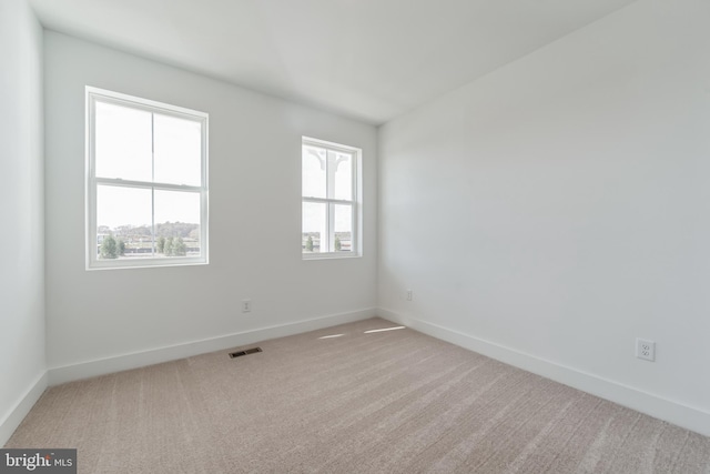 carpeted empty room with visible vents and baseboards