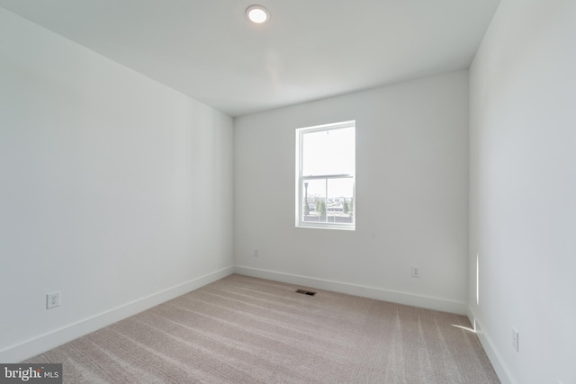 unfurnished room with carpet, visible vents, and baseboards