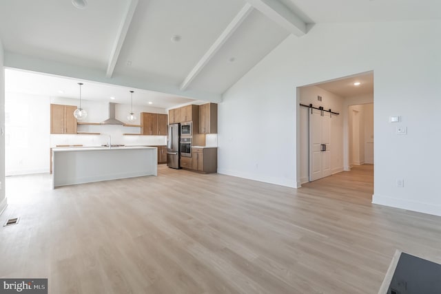 unfurnished living room featuring a barn door, a sink, visible vents, light wood finished floors, and beamed ceiling