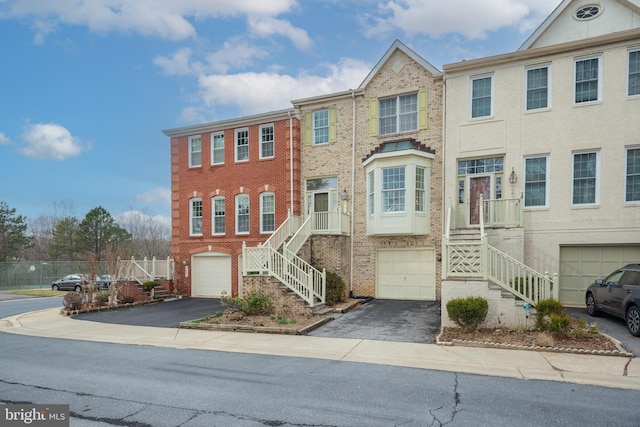 townhome / multi-family property featuring aphalt driveway, brick siding, and stairway